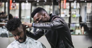 A Somali hairdresser gives a haircut to a customer in the capital Ankara, Turkey, April 12, 2021. (AA Photo)