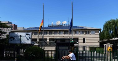A man cycles past the German and EU flags flying at half-mast at the German Embassy in Beijing on Sept. 6, 2021, after the announcement of the death of Germany's ambassador to China Jan Hecker. (AFP Photo)