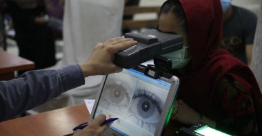 An employee scans the eyes of a woman for biometric data needed to apply for a passport, at the passport office in Kabul, Afghanistan, June 30, 2021. (AP Photo)