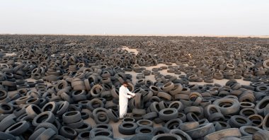 A contractor stands among used tires destined for recycling in Salmi, Kuwait, Sept. 4, 2021. (Reuters Photo)