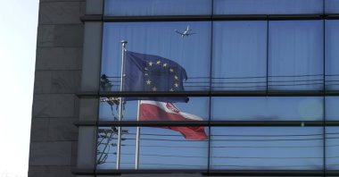 An airplane and flags of Poland and the European Union are reflected on the building of the Embassy of Poland in Tokyo, Aug. 3, 2021. (AP Photo)