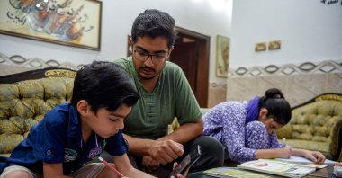 A child uses a mobile phone to attend an online class in Peshawar, Pakistan, Sept. 6, 2021. (Photo by Abdul MAJEED via AFP)