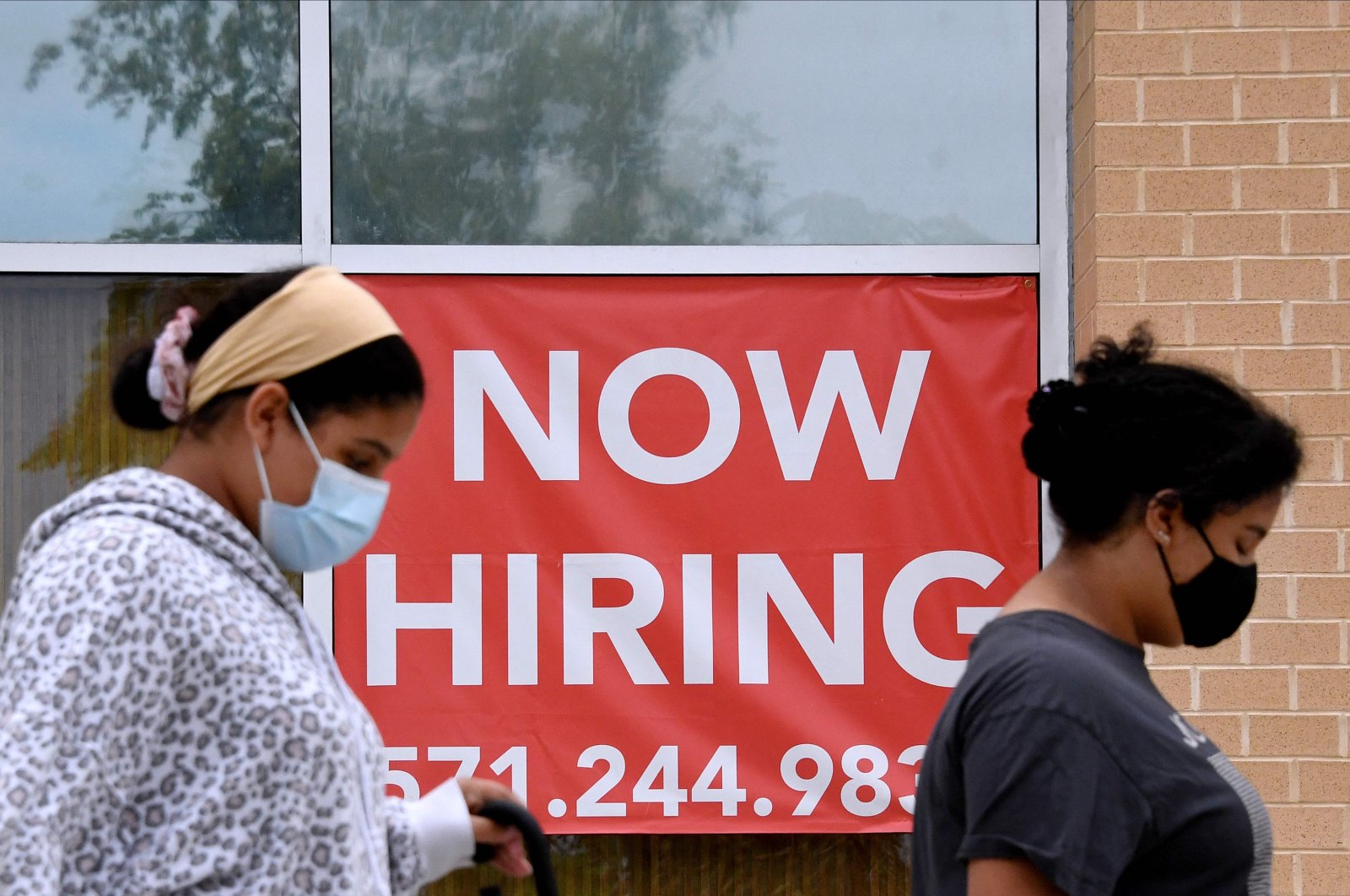 Women walk past by a "Now Hiring" sign outside a store in Arlington, Virginia, U.S., Aug. 16, 2021. (AFP Photo)