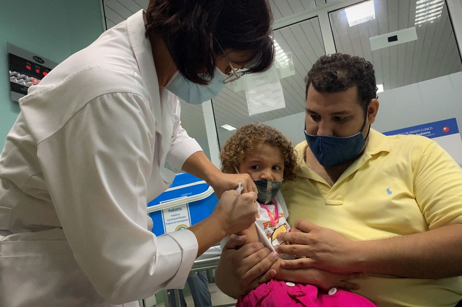 Pedro Montano holds his daughter Roxana Montano, 3, as she is inoculated against COVID-19 with Cuban vaccine Soberana Plus, at the Juan Manuel Marquez hospital in Havana, Cuba, as part of a vaccine study in children and adolescents, Aug. 24, 2021 (Adalberto Roque / AFP Photo)