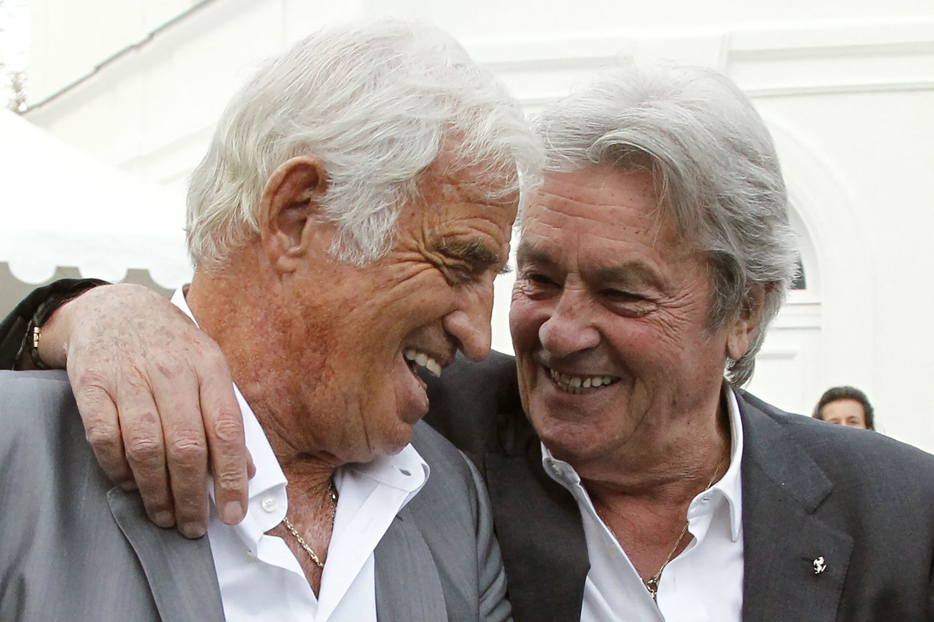 French actor Alain Delon (R) puts his arm around fellow actor Jean-Paul Belmondo in Boulogne-Billancourt during the inauguration of the Paul Belmondo museum dedicated to the work of Jean-Paul Belmondo