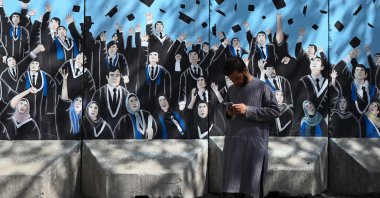 A man uses his mobile phone in front of a mural outside Afghanistan's Ministry of Higher Education, Kabul, Afghanistan, Sept. 9, 2021. (AFP Photo)