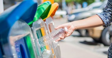 The picture shows a person throwing a plastic bottle in a recycling bin. (Shutterstock Photo)