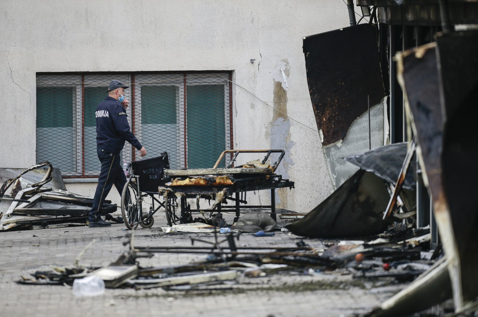 A police officer walks past burned hospital equipment on the site of a destroyed field hospital following a fire in Tetovo, North Macedonia, Sept. 9, 2021. (AP Photo)
