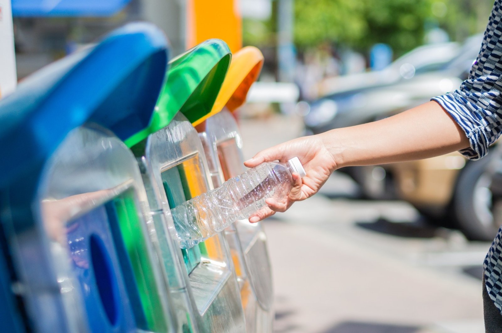 The picture shows a person throwing a plastic bottle in a recycling bin. (Shutterstock Photo)