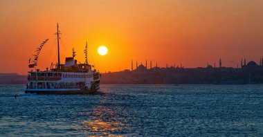 Passenger ferry floats across the Bosporus at sunset, Istanbul, Turkey. (Shutterstock Photo)