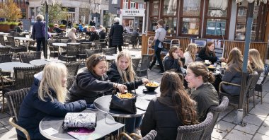 People sit outside a restaurant as cafes and bars are reopened, in Roskilde, Denmark, April 21, 2021. (AP Photo)