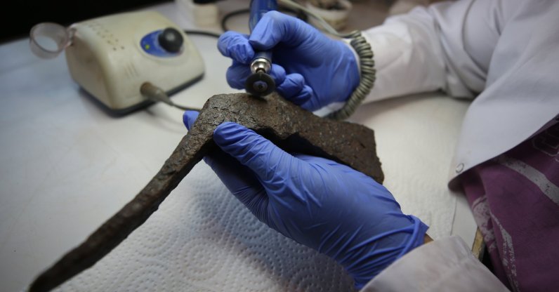 An archaeologist works on the ax found in the ancient city of Assos, Çanakkale, Turkey, Sept. 8, 2021. (AA Photo)
