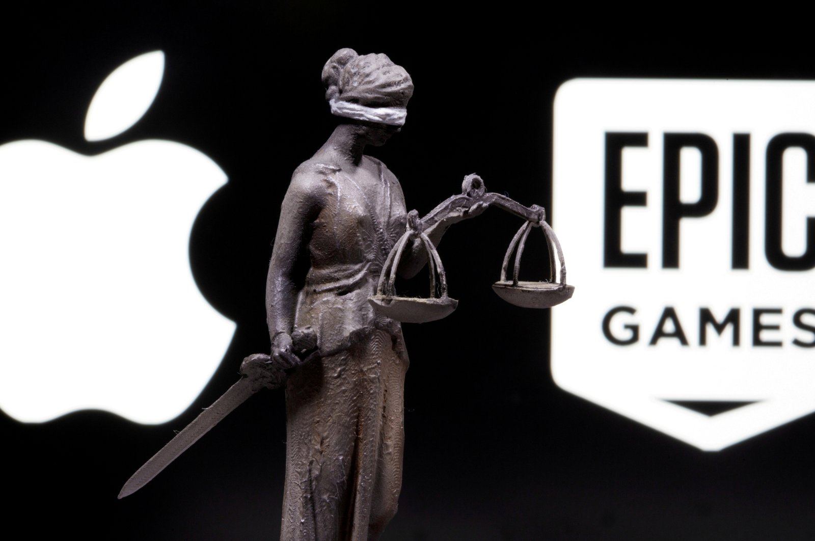 3D printed Lady Justice figure is seen in front of displayed Apple and Epic Games logos in this illustration photo taken Feb. 17, 2021. (Reuters Photo)