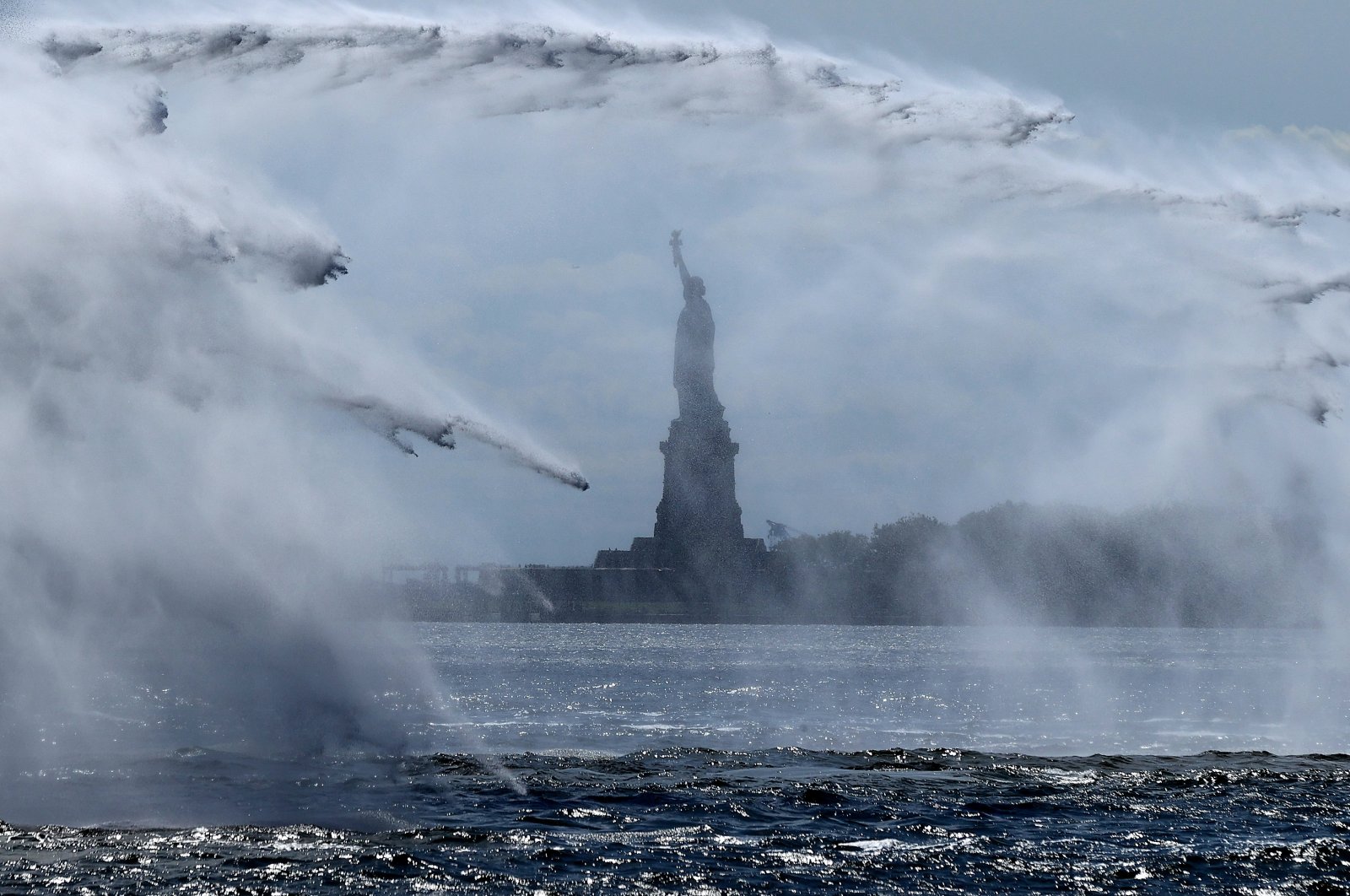 The Statue of Liberty is seen through the spray created during the 20th-anniversary commemoration of 9/11 along Lower Manhattan, New York City., U.S., Sept. 10, 2021. (Photo by Getty Images)