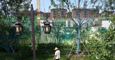 A worker cleans a display area next to the construction site of an Evergrande housing complex in Beijing, China, Sept. 13, 2021. (AFP Photo)