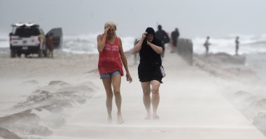 People shield their faces from wind and sand ahead of Tropical Storm Nicholas on the North Packery Channel jetty in Corpus Christi, Texas, U.S, Monday, Sept. 13, 2021. (AP Photo)