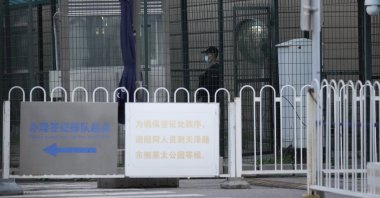 A security officer stands guard behind fences around the U.S. Embassy in China near a signboard directing visa applicants, Beijing, China, Sept. 6, 2021. (AP Photo)