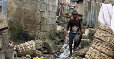 A boy walks past sewage around houses in Abuja, Nigeria, Sept. 3, 2021. (AP Photo)
