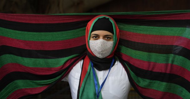 An Afghan refugee living in India wearing a scarf in the colors of the Afghan flag participates in a protest against the Taliban takeover of Afghanistan outside the office of the United Nations High Commissioner for Refugees, in New Delhi, India,  Aug. 23, 2021. (AP Photo)