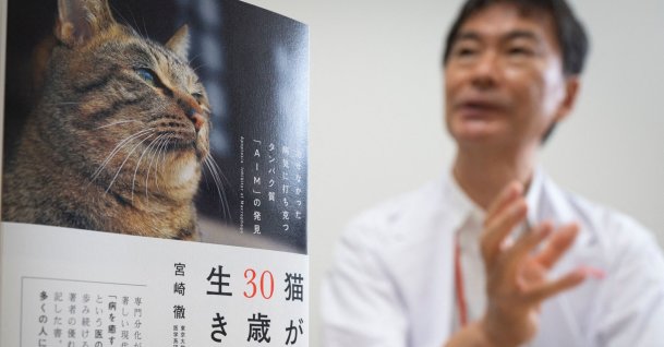 Immunology professor Toru Miyazaki explaining his study behind a copy of his book (L) during an interview with AFPBB News at the University of Tokyo, Tokyo, Japan, July 30, 2021. (AFPBB News via AFP)