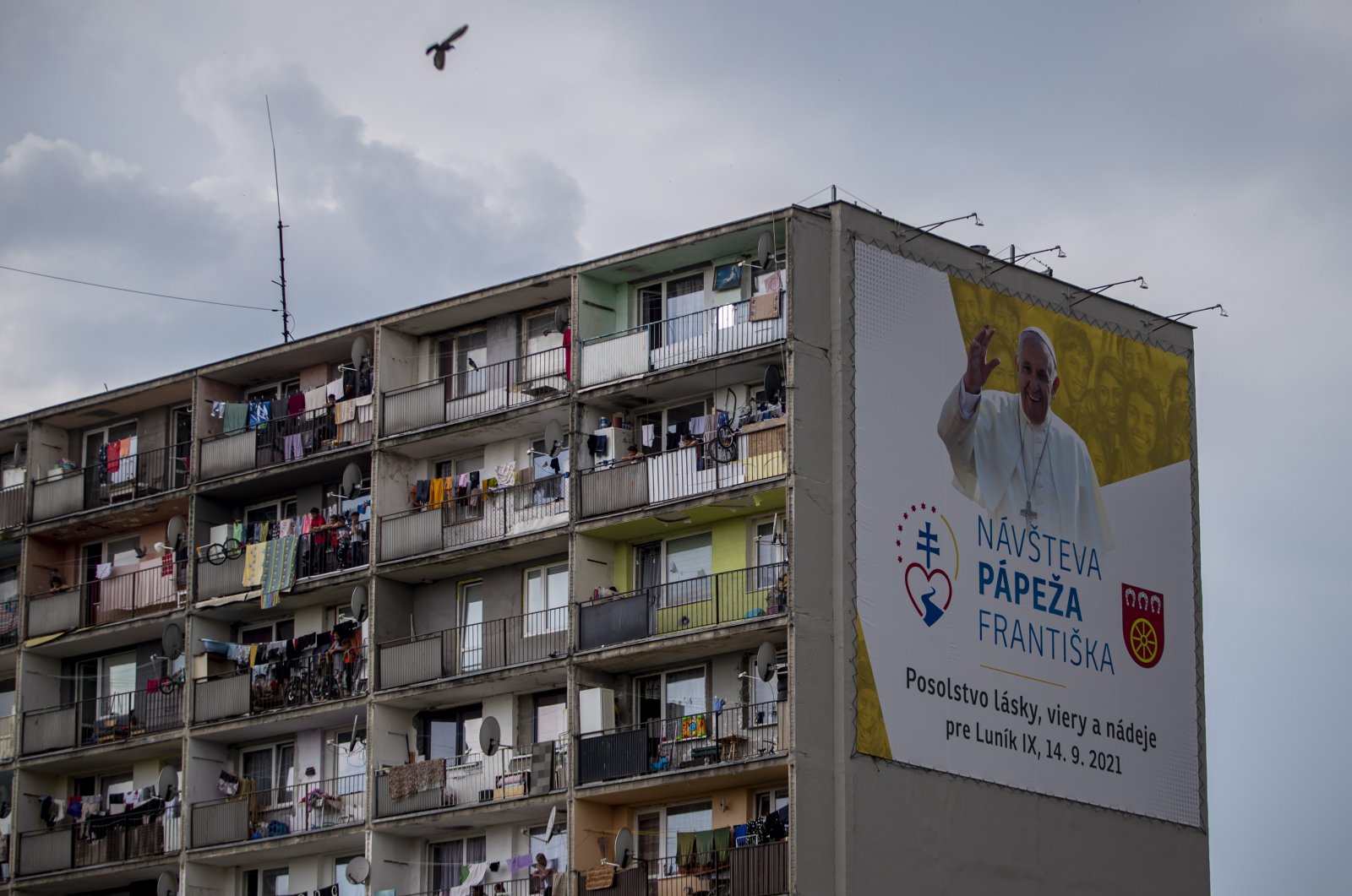 People look out from a Roma settlement at Lunik IX district with a large billboard showing an image of Pope Francis, Kosice, Slovakia, Sept. 13, 2021. (EPA Photo)