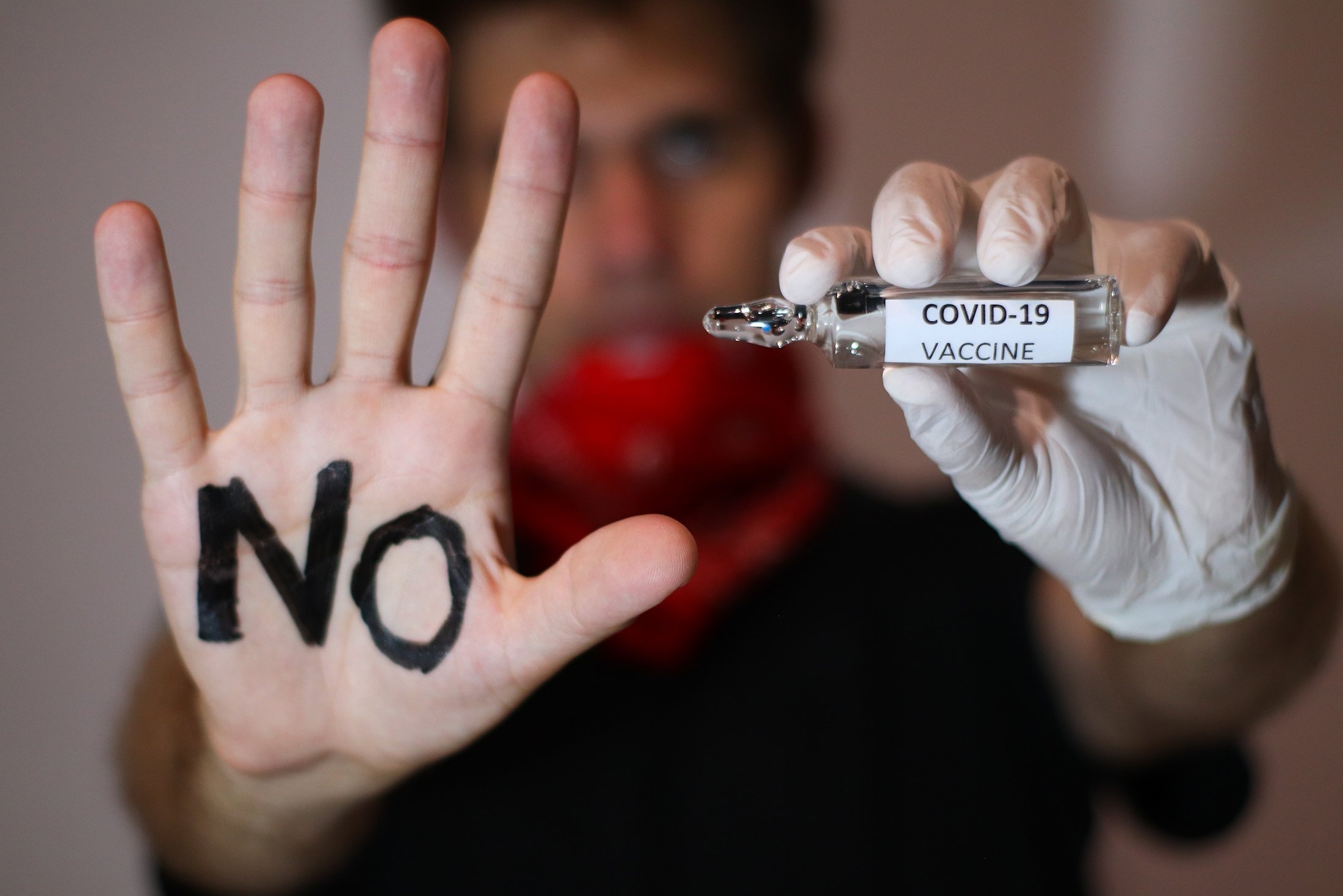 An anti-vaccine protester holding a tube labeled 'COVID-19 Vaccine.' (Shutterstock Photo)