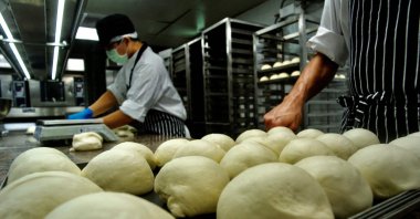 Employees from Taiwan company Just Kitchen, a network of "ghost kitchens" that make delivery-only food, preparing to bake bread for takeaway meals at one of their locations in Taipei, Taiwan, Aug. 18, 2021. (Sam Yeh / AFP Photo)