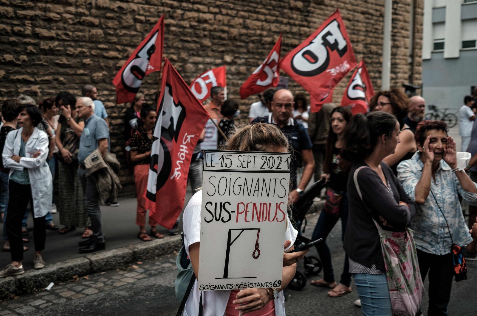 A nursing staff member holds a sign as she demonstrates in front of The A.R.S (regional health agency) against mandatory health passport "pass sanitaire" obligation for hospital workers which the government is attempting to enforce to fight the coronavirus, Lyon, south-eastern France, Sept. 14, 2021.  (AFP Photo)