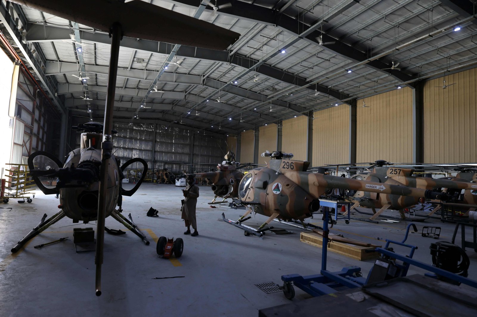 A Taliban fighter stands next to damaged Afghan Air Force helicopters at a hangar at Kabul airport on Sept. 14, 2021. (AFP Photo)