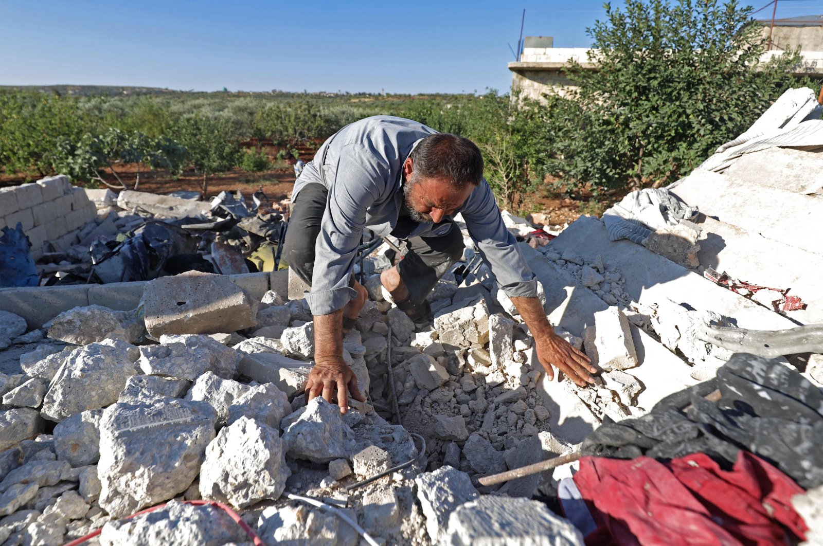 A man searches through rubble in the aftermath of Syrian regime forces' bombardment on the town of Balashun, south of Idlib province, Syria, on Aug. 19, 2021. (AFP Photo)