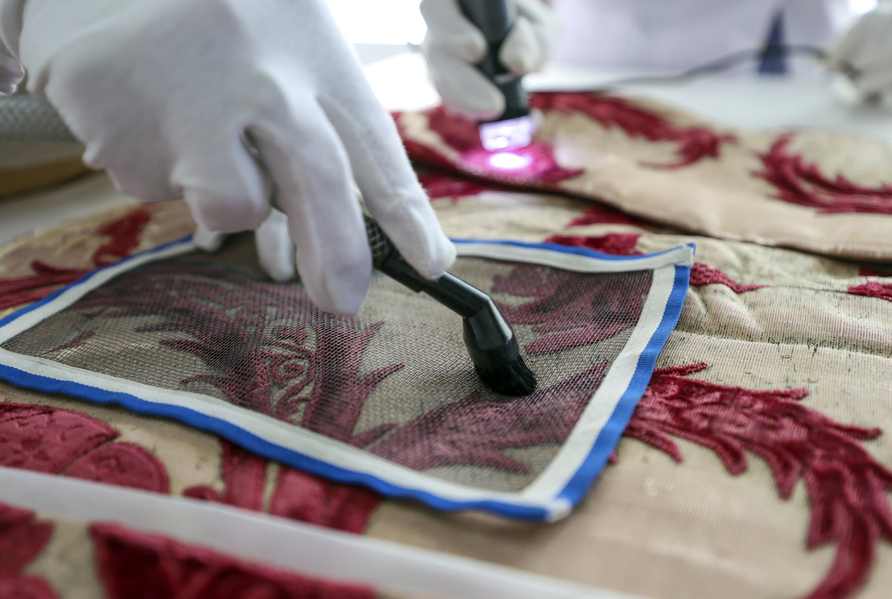 A close-up of a hand of a restorer while working on Sultan Suleiman I