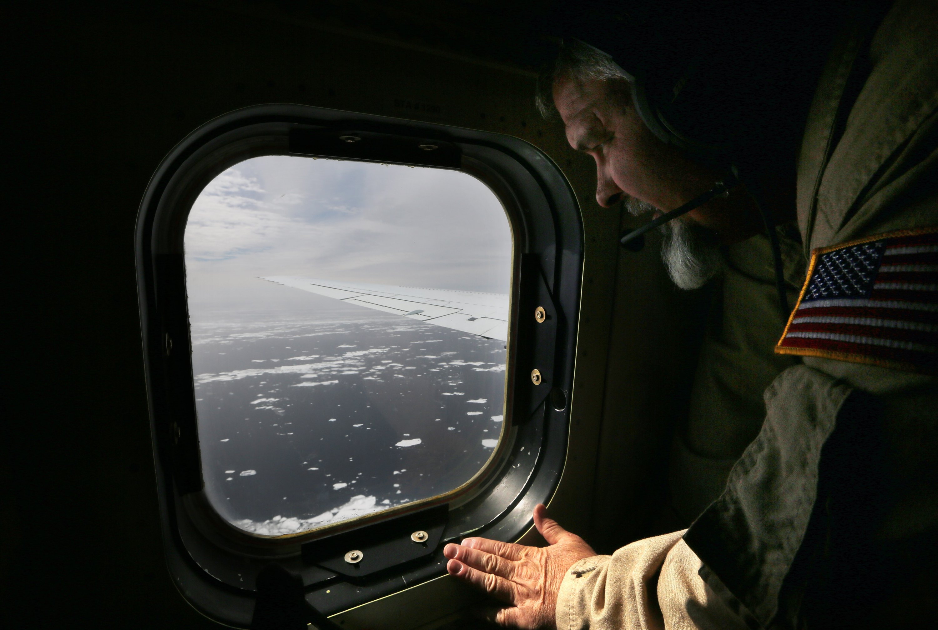 Lyn Lohberger of NASA looks out as sea ice floats near the coast of West Antarctica from a window of a NASA Operation IceBridge airplane on October 27, 2016 in-flight over Antarctica. (Getty Images)