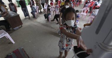 A young girl disinfects her hands before receiving a shot of Sinovac's COVID-19 vaccine at a Samrong Krom health center outside Phnom Penh, Cambodia, Sept. 17, 2021.  (AP Photo)