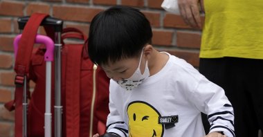 A child wearing a face mask plays a game on a smartphone next to his relative in Beijing, China, Sept. 12, 2021. (AP Photo)