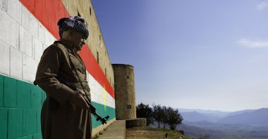 A Peshmerga fighter poses in front of a wall with a large fresco of the flag of the Kurdistan Regional Government (KRG), Dohuk, northern Iraq, Feb. 14, 2016. (Getty Images)