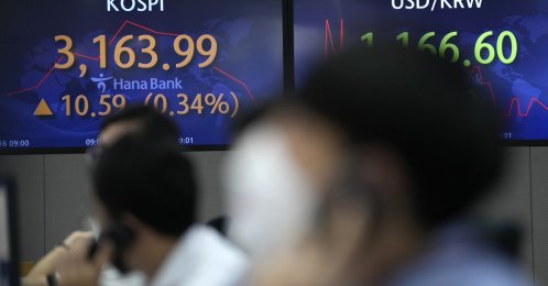 Currency traders talk on phones near screens showing the Korea Composite Stock Price Index (KOSPI), at a foreign exchange dealing room in Seoul, South Korea, Sept. 16, 2021. (AP Photo)
