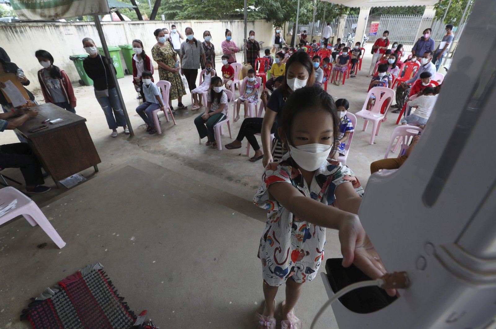 A young girl disinfects her hands before receiving a shot of Sinovac's COVID-19 vaccine at a Samrong Krom health center outside Phnom Penh, Cambodia, Sept. 17, 2021.  (AP Photo)
