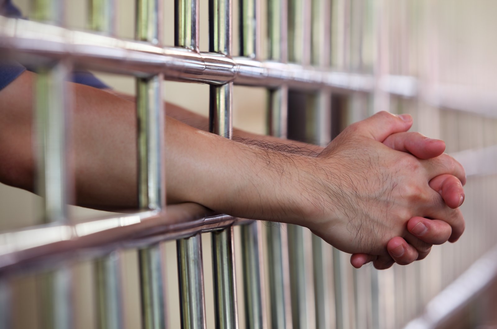 An inmate rests his hands on the bars of his cell. (Shutterstock Photo)