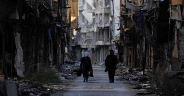 This file photo shows women walking past damaged buildings at the Yarmouk Palestinian refugee camp on the southern outskirts of Damascus, Syria, Dec. 1, 2020. (Reuters Photo)