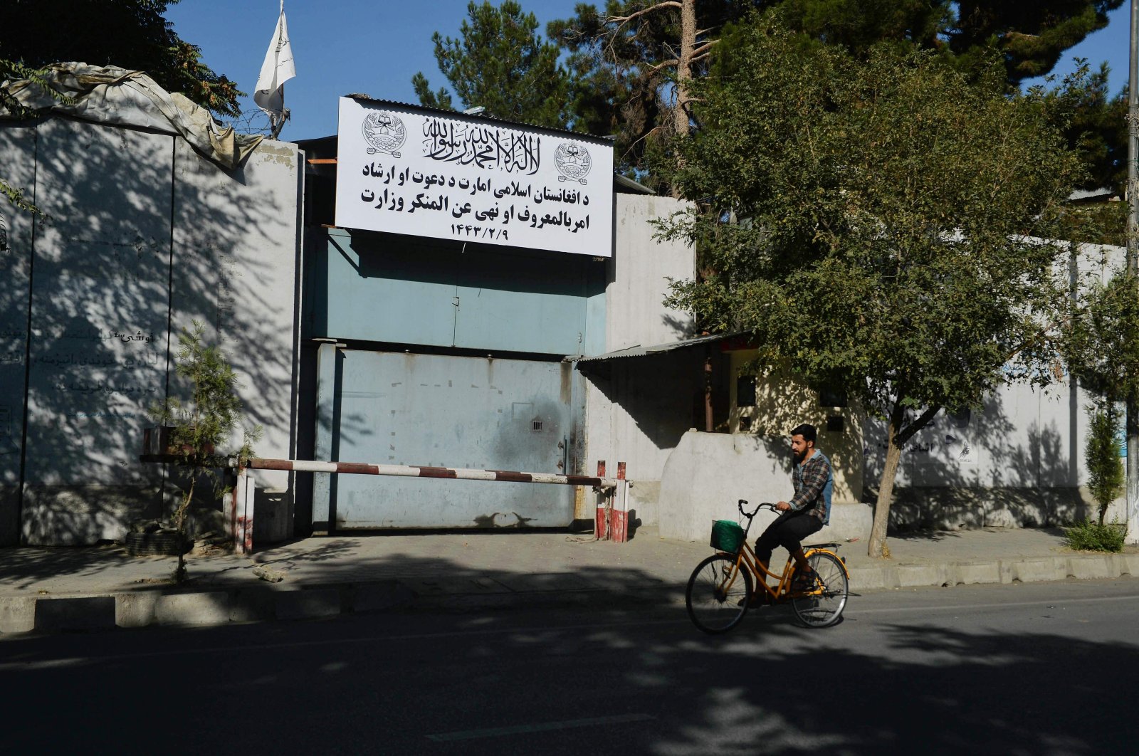 A man rides his bike past an entrance gate of the Ministry for the Promotion of Virtue and Prevention of Vice in Kabul, Afghanistan, Sept. 17, 2021. (Photo by Hoshang Hashimi via AFP)