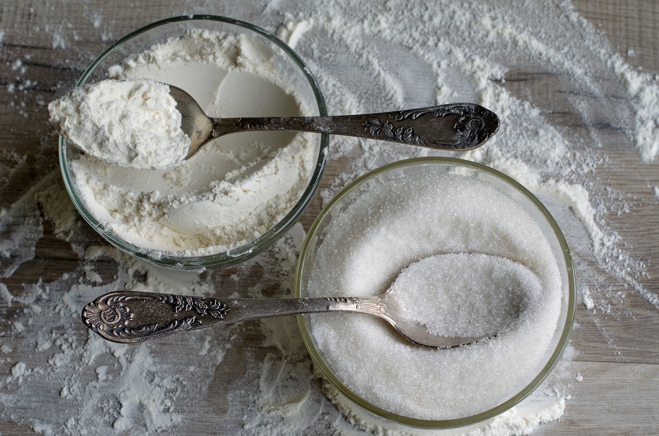 Two silver tablespoons of sugar and flour for cooking a cake. (Shutterstock)