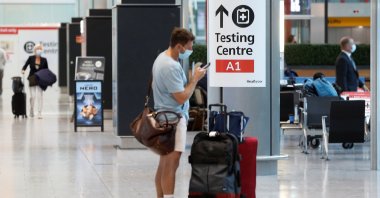 A passenger stands next to a COVID-19 testing center sign in the international arrivals area of Terminal 5 in London's Heathrow Airport, Britain, Aug. 2, 2021. (Reuters Photo)