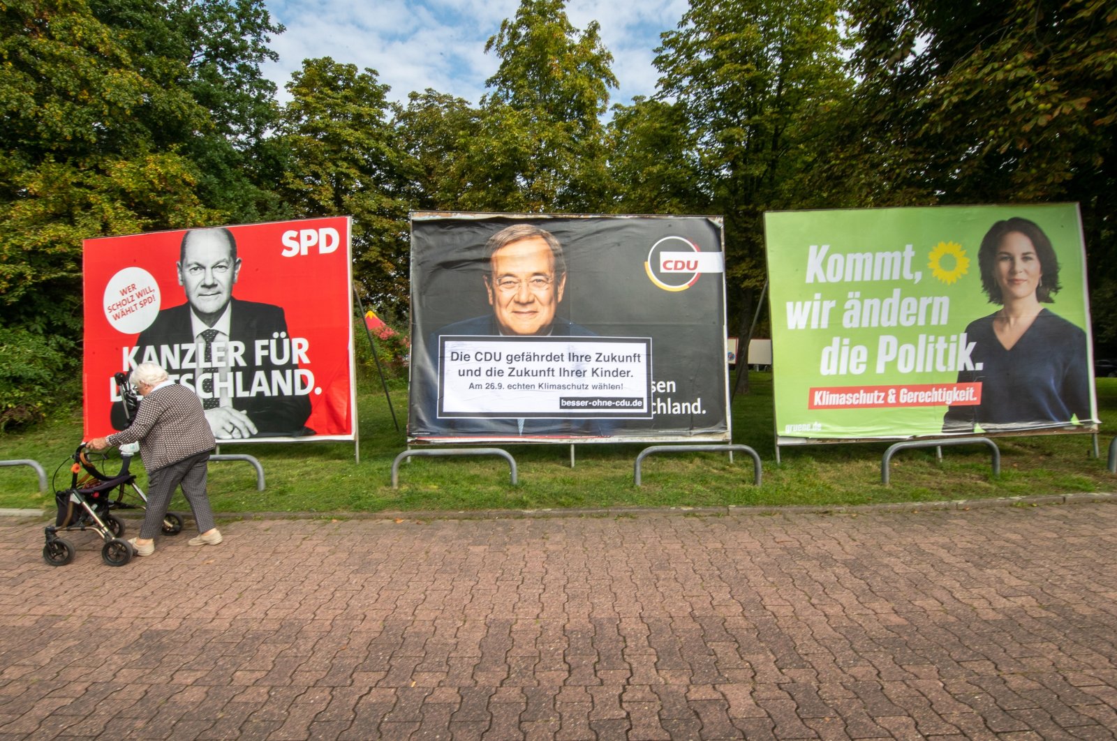 An elderly woman walks past large election placards of the three leading candidates in the German federal elections (L-R) Olaf Scholz of the Social Democratic Party (SPD), Armin Laschet of the Christian Democratic Union (CDU) and Annalena Baerbock of the Green Party (Buendnis 90/Die Gruenen) in Frankfurt am Main, Germany, Sept. 17, 2021. (EPA Photo)
