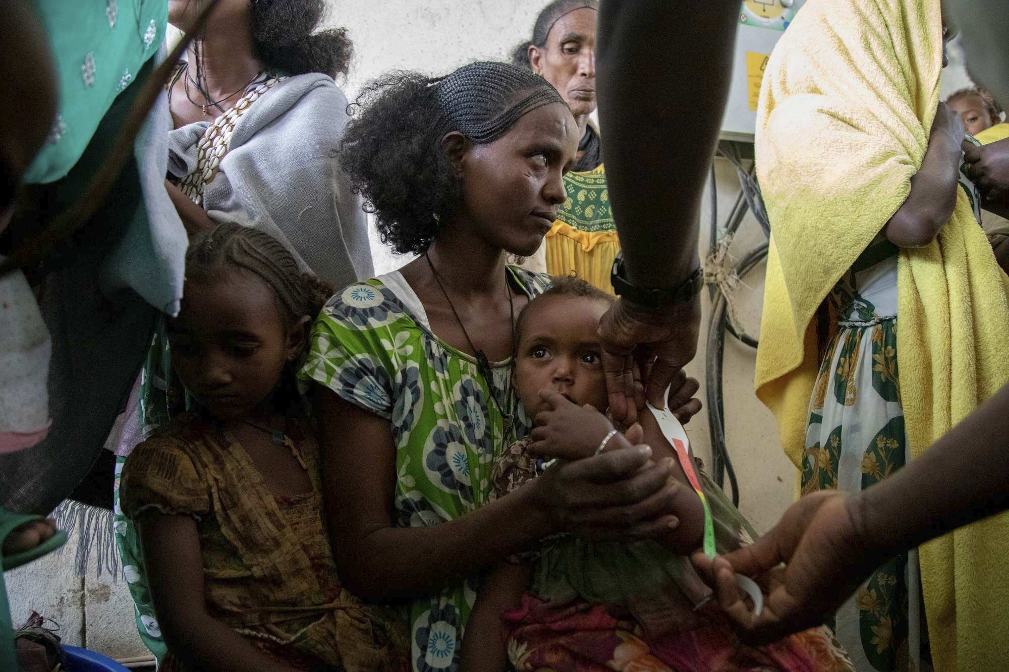 A woman holds a child during a screening for malnutrition in pregnant and lactating women by UNICEF and partners in Gijet, the Tigray region, northern Ethiopia, July 20, 2021. (AP Photo)
