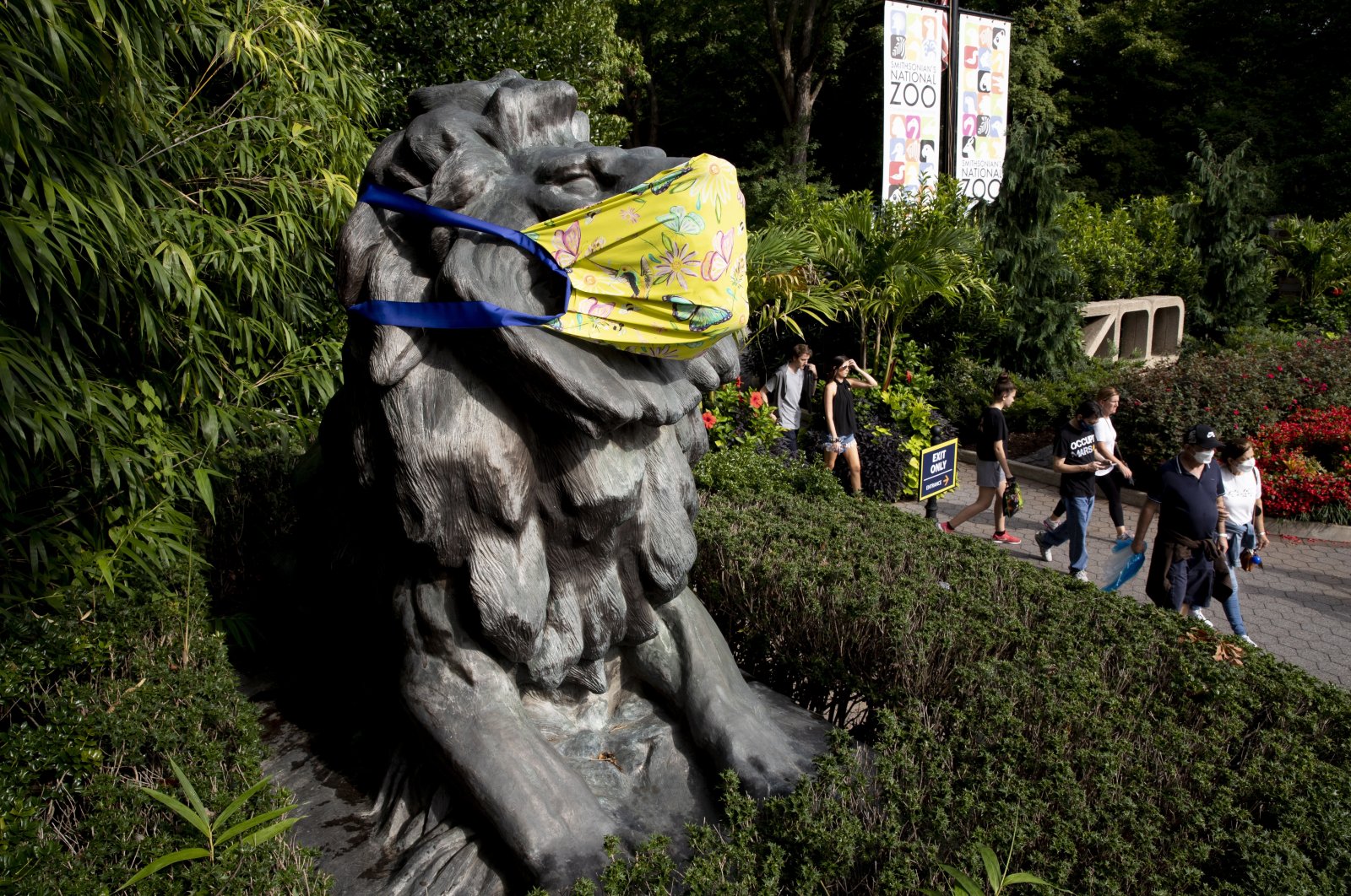 People exit the Smithsonian National Zoological Park beside a statue of a lion that is decorated with a face mask, Washington, D.C., U.S., Sept. 17, 2021. (EPA Photo)