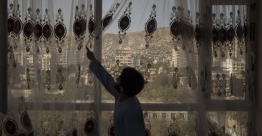Mohammed Zakir closes the curtains of his family home, overlooking Kabul, Afghanistan, Sept. 17, 2021. (AP Photo)