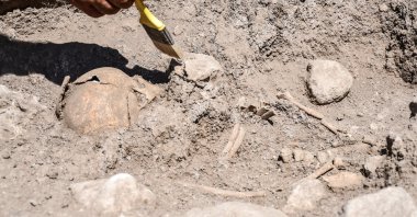 An archaeologist works on the skeleton of a child at Domuztepe Mound, Kahramanmaraş, southern Turkey, Sept. 20, 2021. (AA Photo)