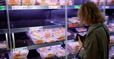 A customer looks at packages of chilled chicken cuts in a half-empty refrigerated display unit at a Lidl supermarket store in Walthamstow, west London, Sept,  21, 2021. (AFP Photo)
