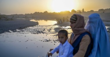 A family rides past a river on a motorcycle in Kandahar, Afghanistan, Sept. 23, 2021. (AFP Photo)