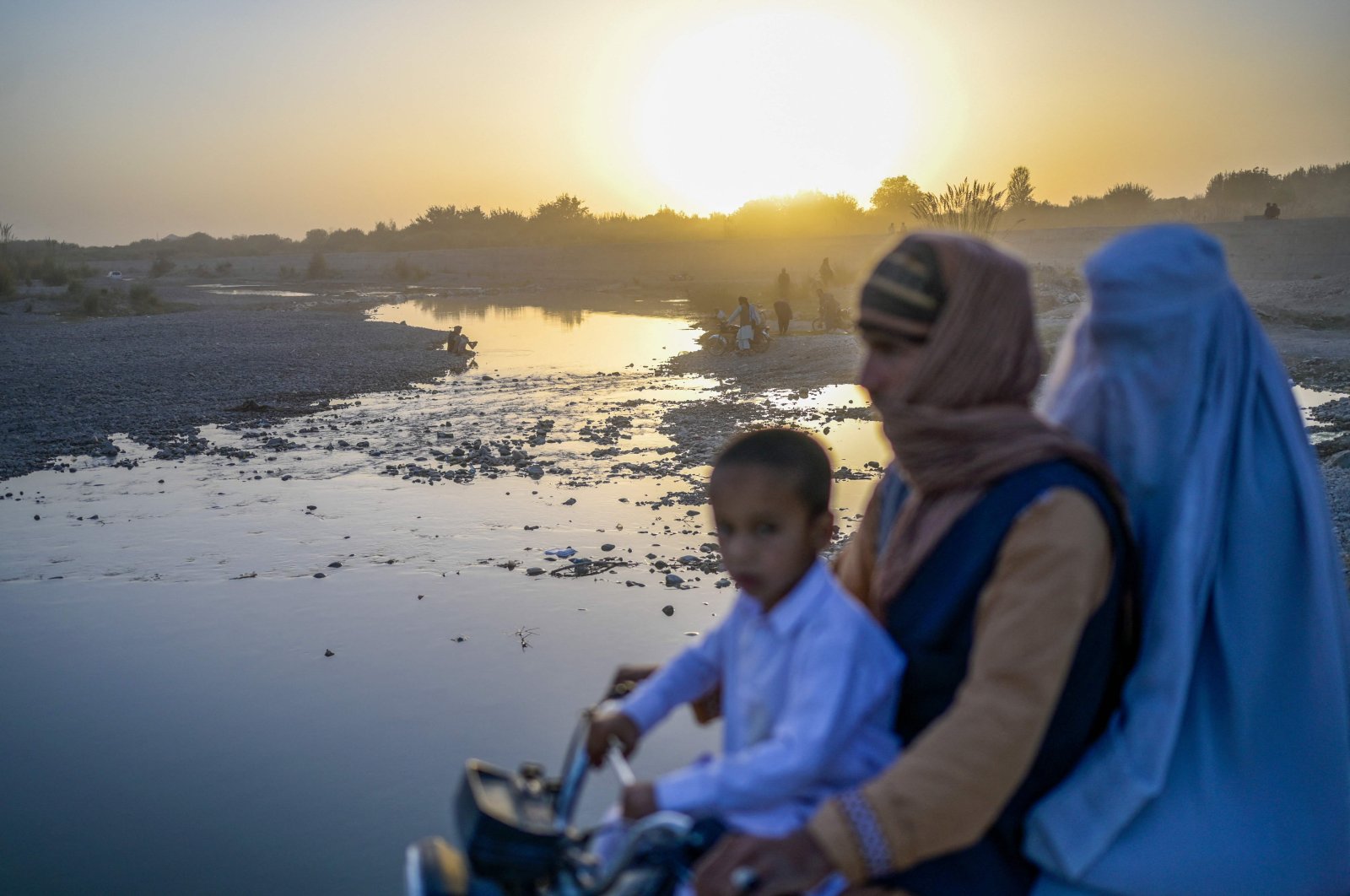 A family rides past a river on a motorcycle in Kandahar, Afghanistan, Sept. 23, 2021. (AFP Photo)